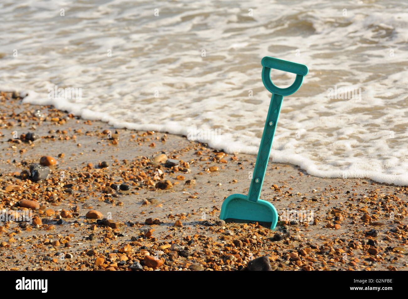 Foto eines Kindes Spaten in den Sand am Strand mit dem Meer im Hintergrund Stockfoto