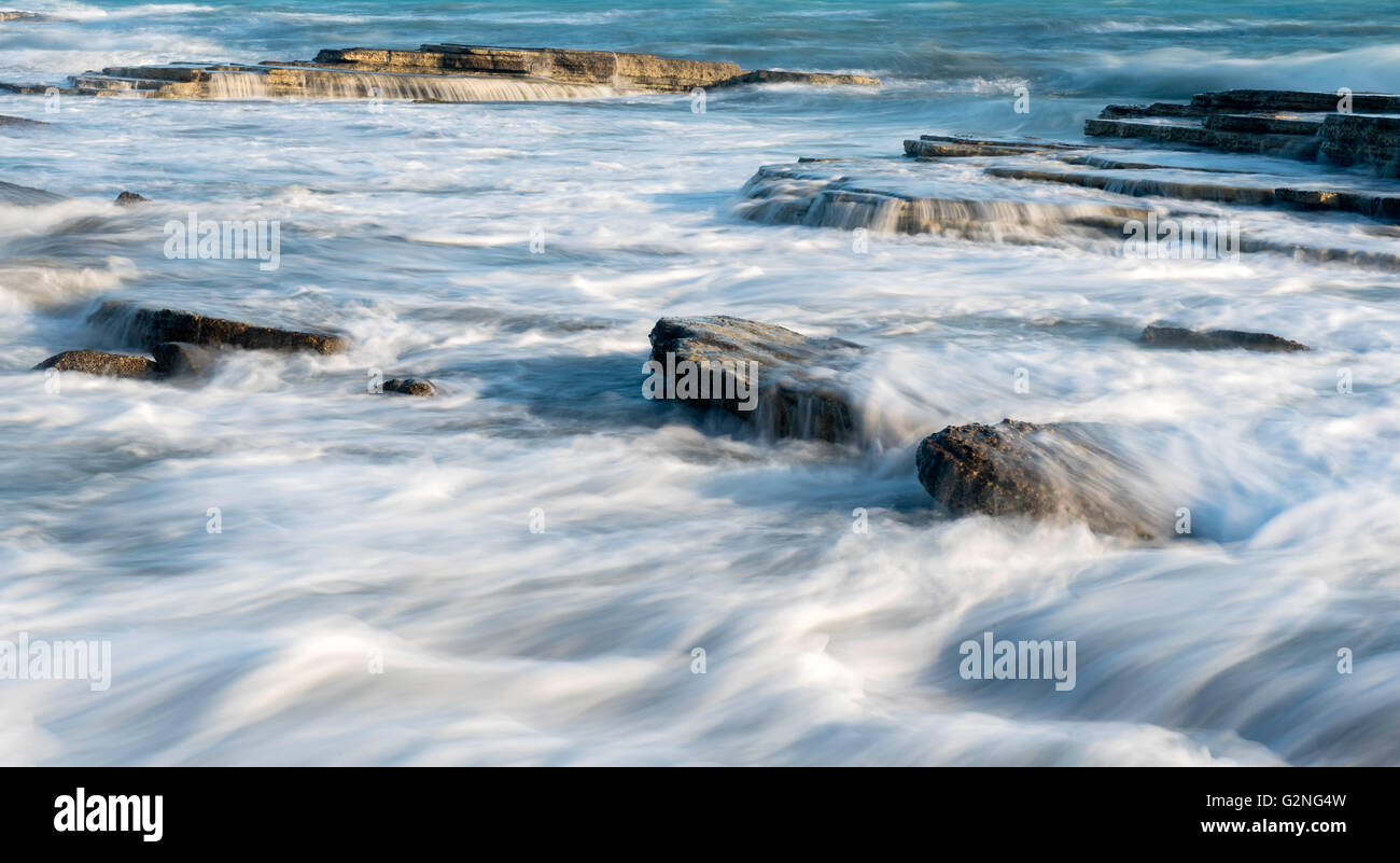 Meereswellen an Platten von Meer-Felsen, kleinen Wasserfällen und glatte Ströme von Wasser zu schaffen. Stockfoto