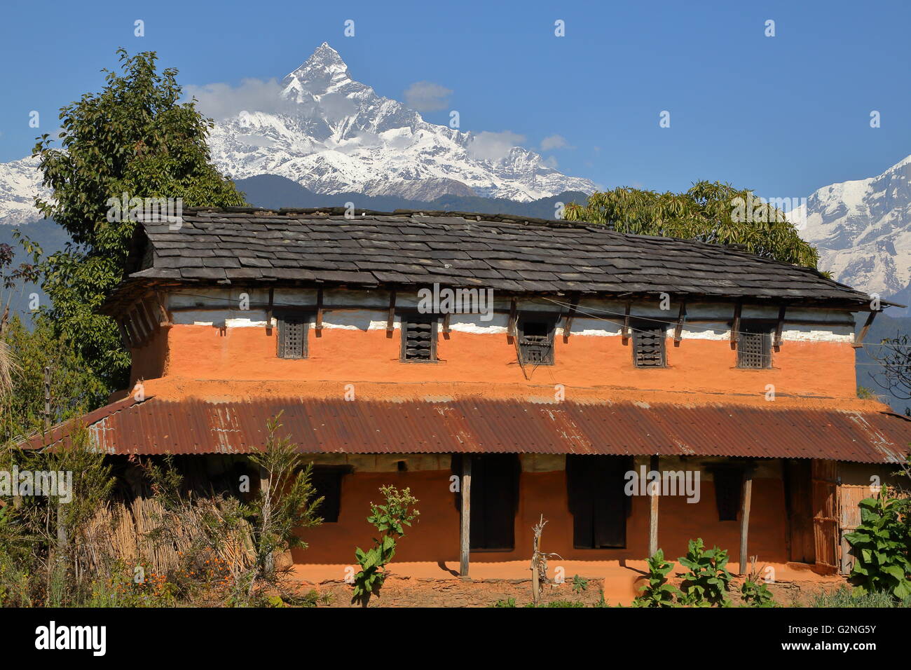 Traditionelles Haus mit Machapuchare Peak im Hintergrund, Annapurna Alpenvorland in der Nähe von Dhampus, Pokhara, Nepal Stockfoto