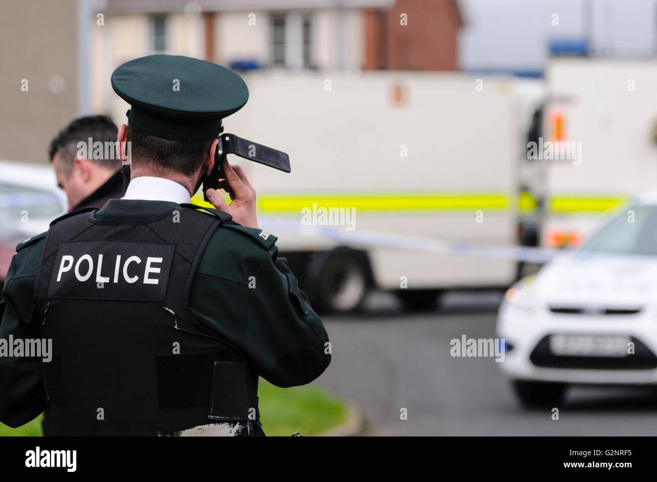 Ein Polizist PSNI macht einen Telefonanruf bei einer Bombe Schrecken Sicherheitswarnung in Rathcoole, Nordirland, Vereinigtes Königreich 26.02.2012 Stockfoto