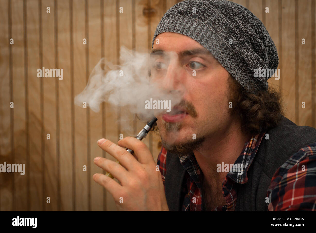 Langhaariger, bärtige Mann raucht eine Vape e-Zigarette Stockfoto