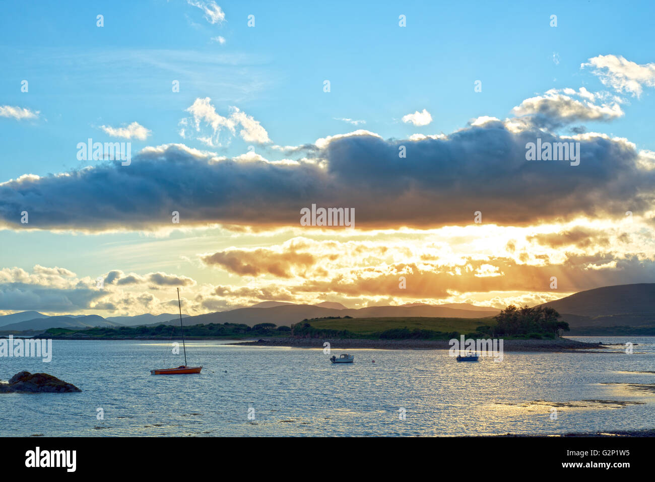 Boote in einer ruhigen Bucht mit Insel in der Nähe von Kenmare am Wilden Atlantik Way Irland mit einer orange Sunset Stockfoto
