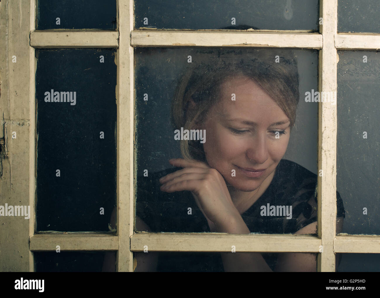 Porträt einer Blone Erwachsene Frau mit alten rustikalen Fenster Stockfoto