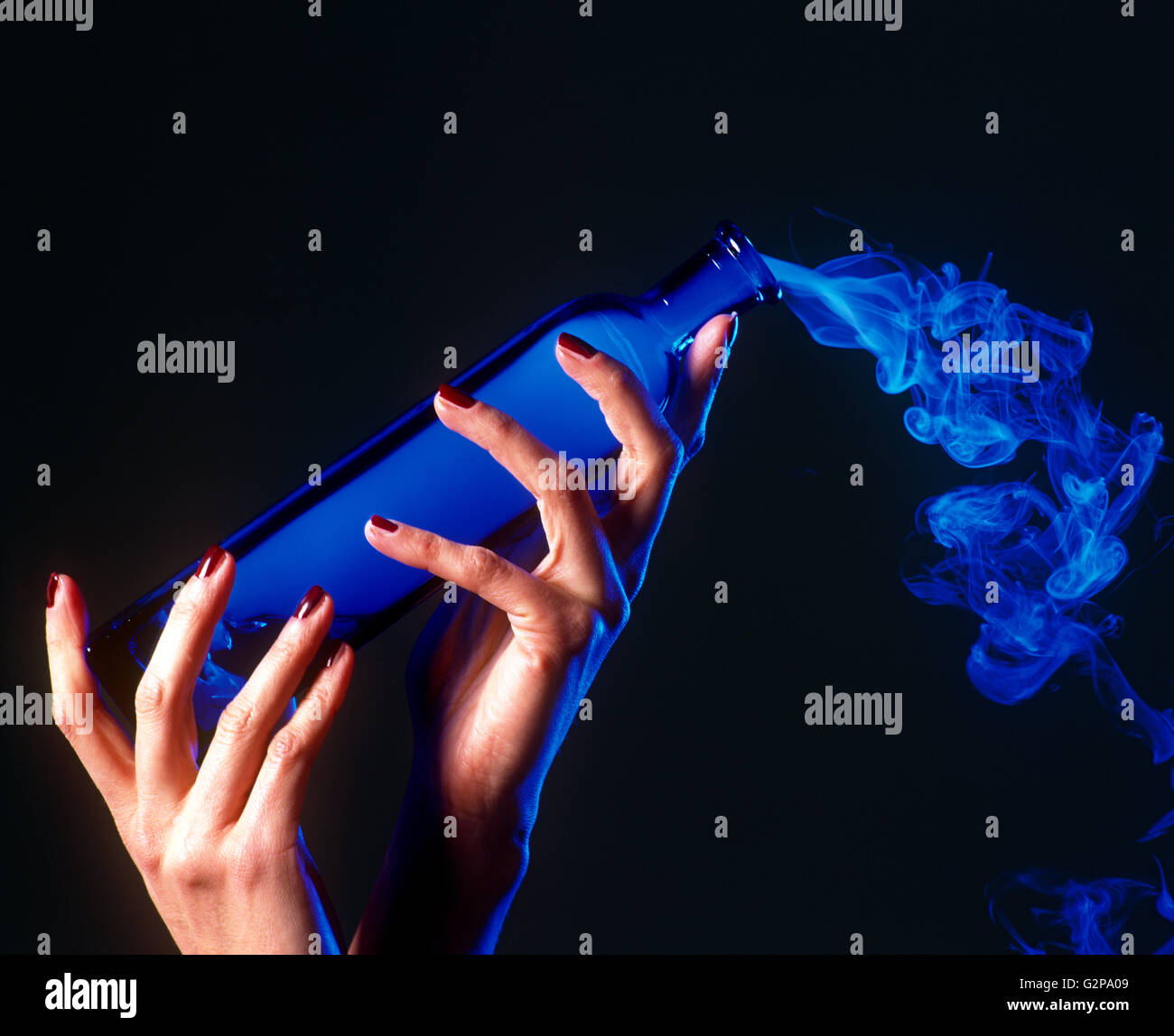 Ein Mädchen-Hände halten eine Flasche blau Rauch, drinnen. Stockfoto