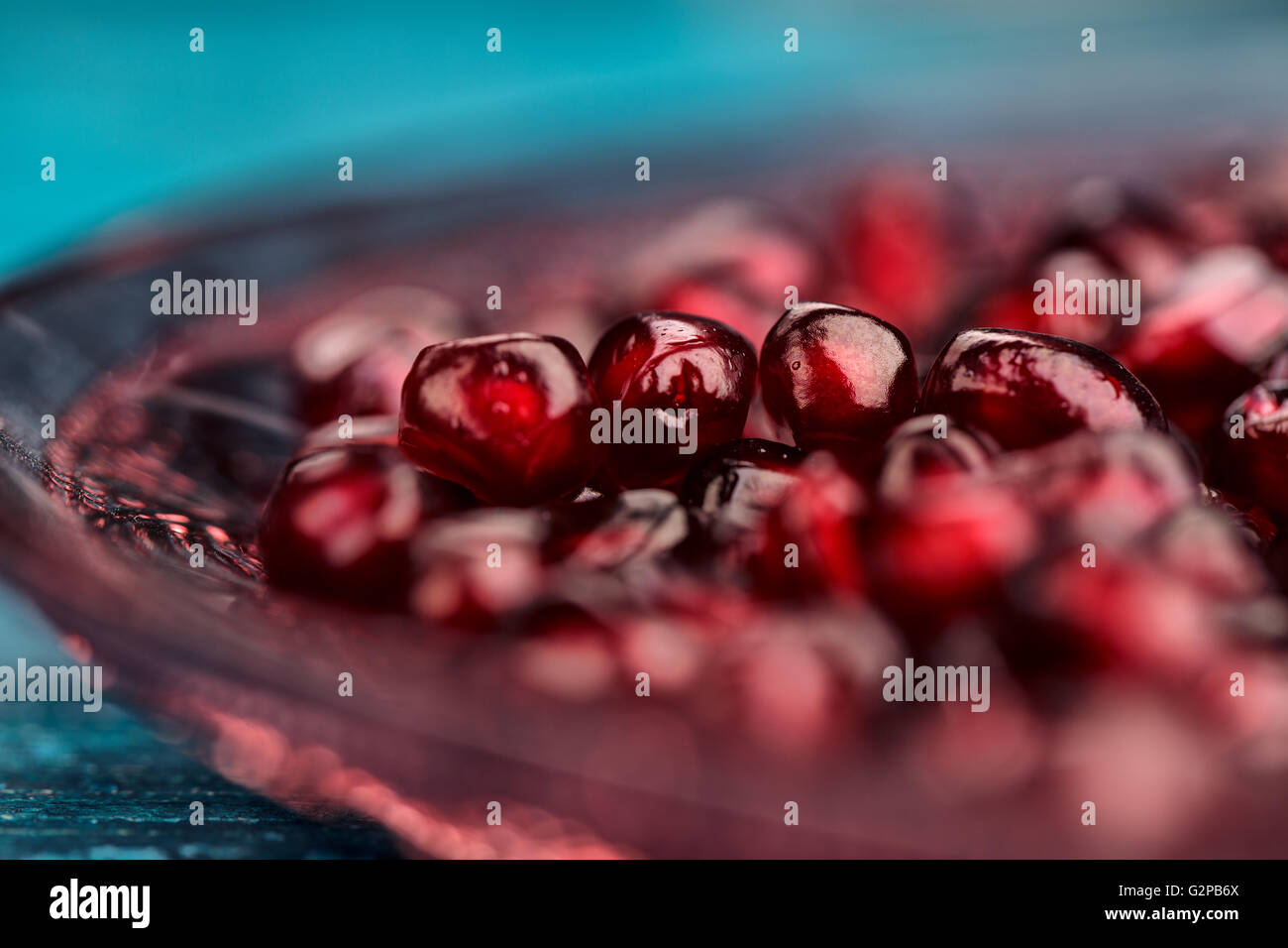 Frische helle rote Granatapfel Grenadine Obst Samen auf blauen hölzernen Hintergrund stilleben Studio gedreht Stockfoto