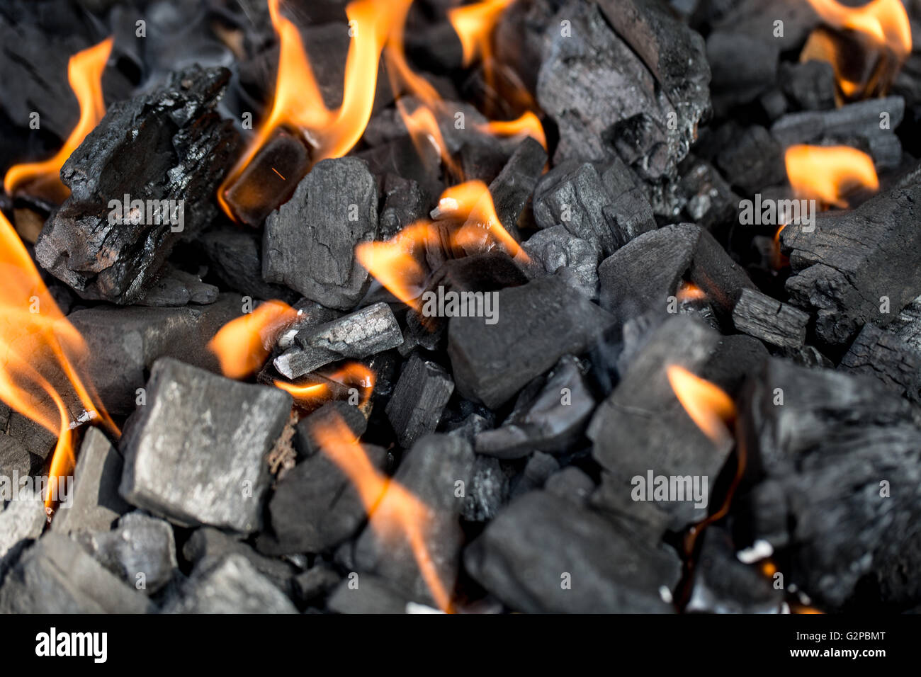 Holzkohle zum Grillen mit leuchtend orangefarbenen Flammen entzünden Stockfoto