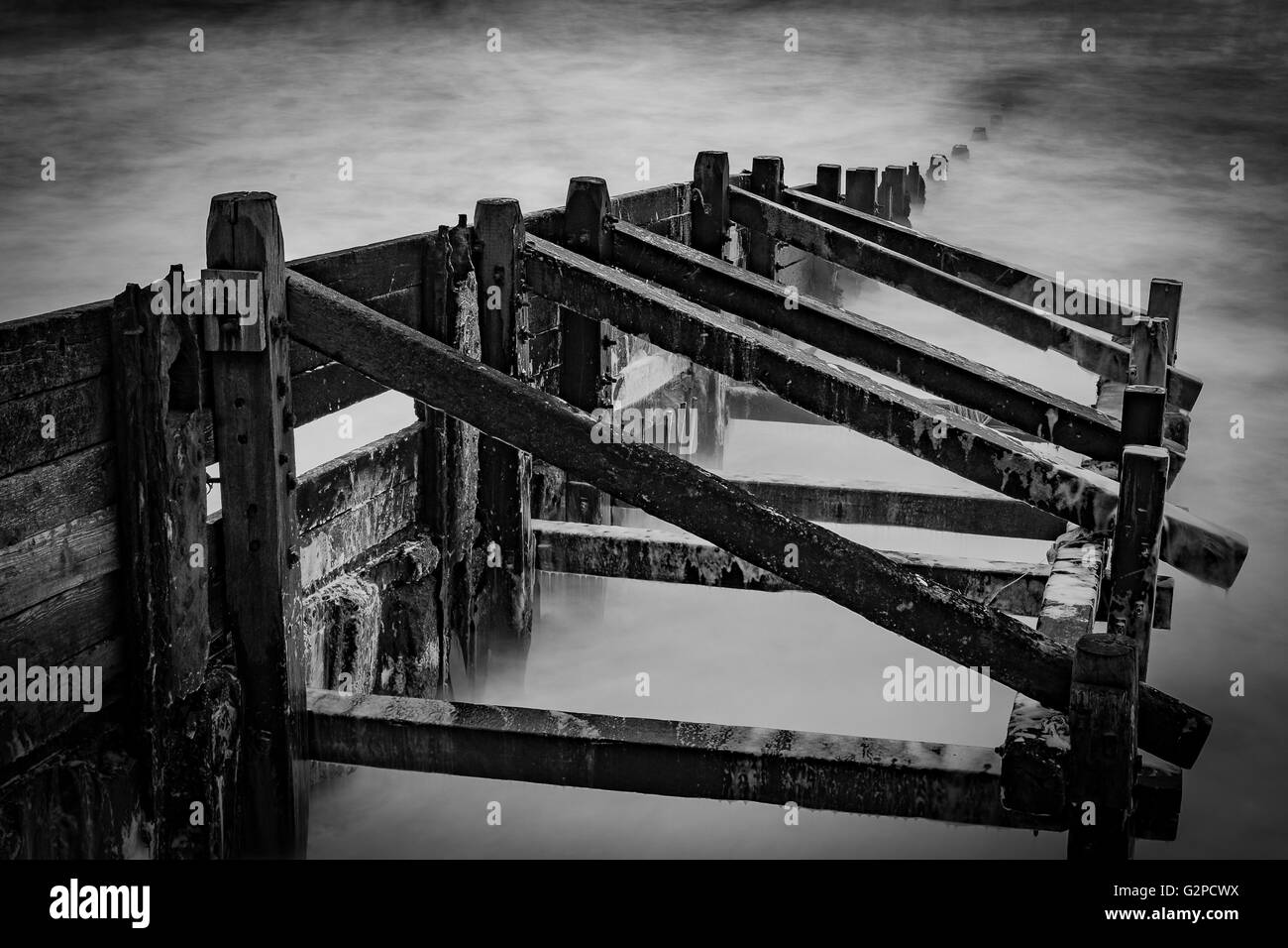 Wellen schlagen gegen einen Steg und Meeresverteidigung, lange Exposition schaffen seidig glattes Wasser an der North Norfolk Küste in Sheringham Stockfoto
