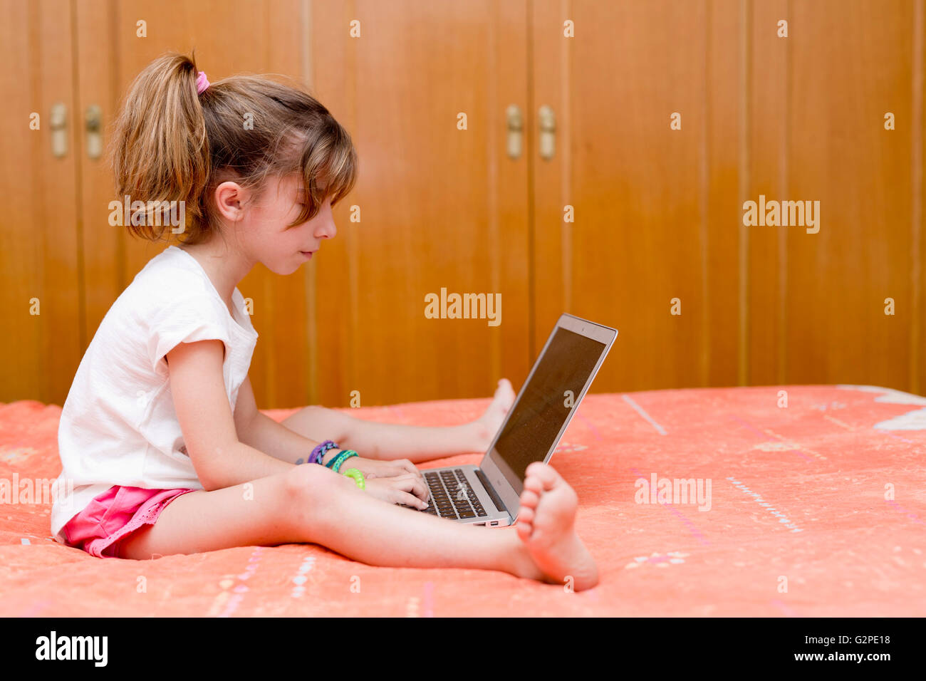 Mädchen sitzen auf einem Bett mit dem Laptop lernen Stockfoto