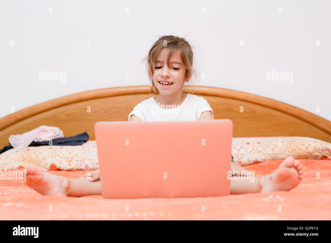 Mädchen sitzen auf einem Bett mit dem Laptop lernen Stockfoto