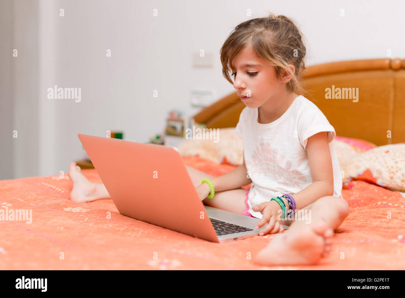Mädchen sitzen auf einem Bett mit dem Laptop lernen Stockfoto