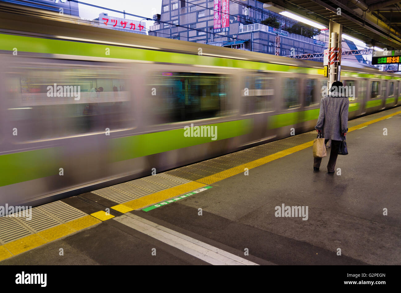 Japan, Tokio, Okachimachi, JR Bahnhof Seniorin auf Plattform als Yamanote Linie Zug fährt geht. Stockfoto