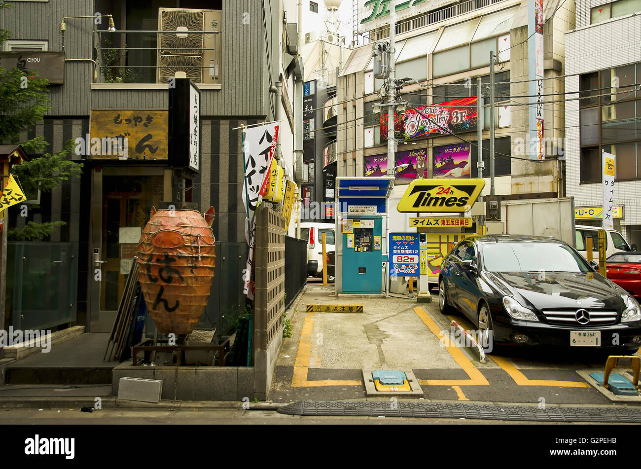 Japan, Tokio, Gotanda JR-Bahnhof, Gebäude mit Restaurants, darunter Vietnamesisch, Zeichen und Laternen, große Chochin Laterne wie Schwein, Parkplatz mit schwarzen Mercedes-Benz. Stockfoto