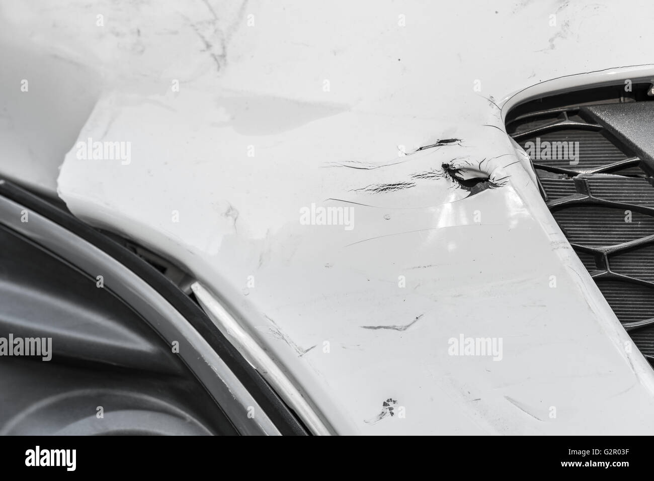 Verbeulte Wunden und Kratzer auf ein beschädigtes weißes Auto Stockfoto