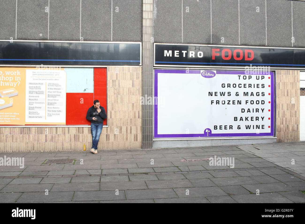 Mann stand an der Wand auf dem Torbogen-Platz in der Nähe ein Zeichen/Anzeige für das Metro-Essen / Convenience store Stockfoto