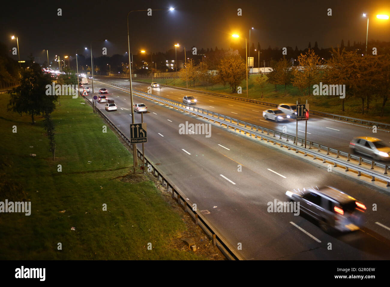 In der Nacht fahren Autos, unter einer Brücke auf der Ringstraße A406 North Circular. Stockfoto