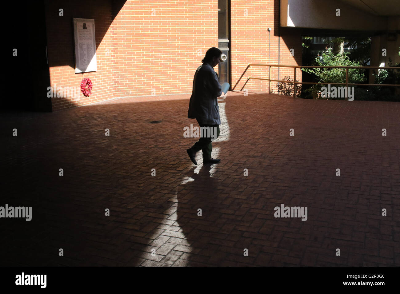 Frau verlässt Kensington Town Hall in London, gefangen im Schatten/Licht Stockfoto