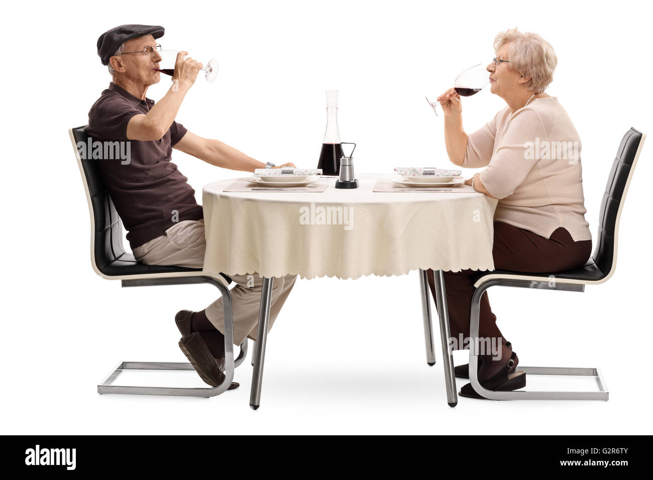 Älterer Mann und Frau trinken Rotwein und sitzt auf einem Datum isoliert auf weißem Hintergrund Stockfoto