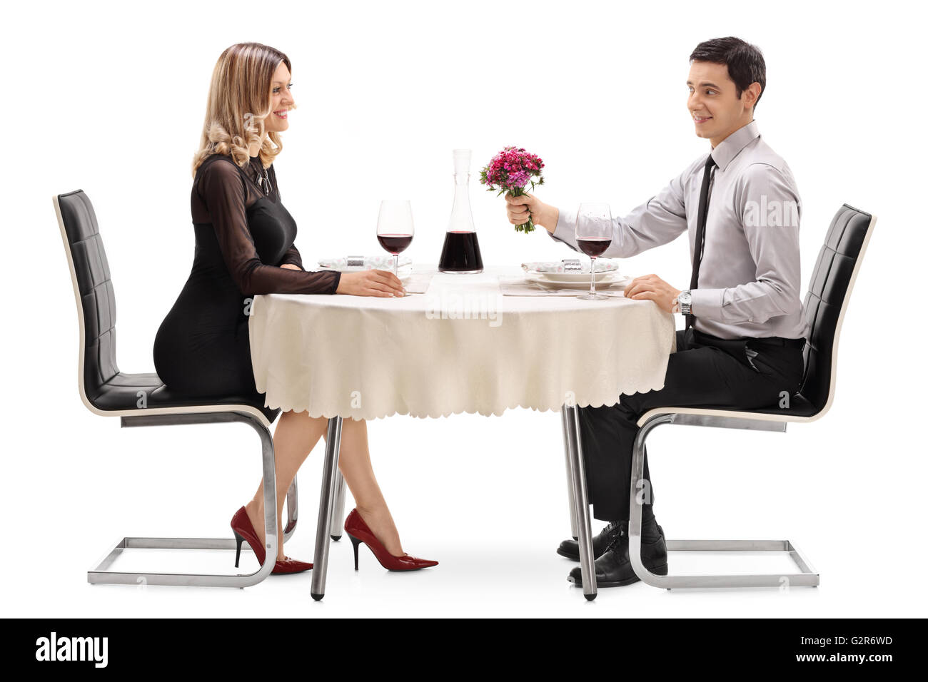 Romantischer Kerl sitzt auf ein Datum mit einer blonden Frau und gab ihr eine Blume isoliert auf weißem Hintergrund Stockfoto