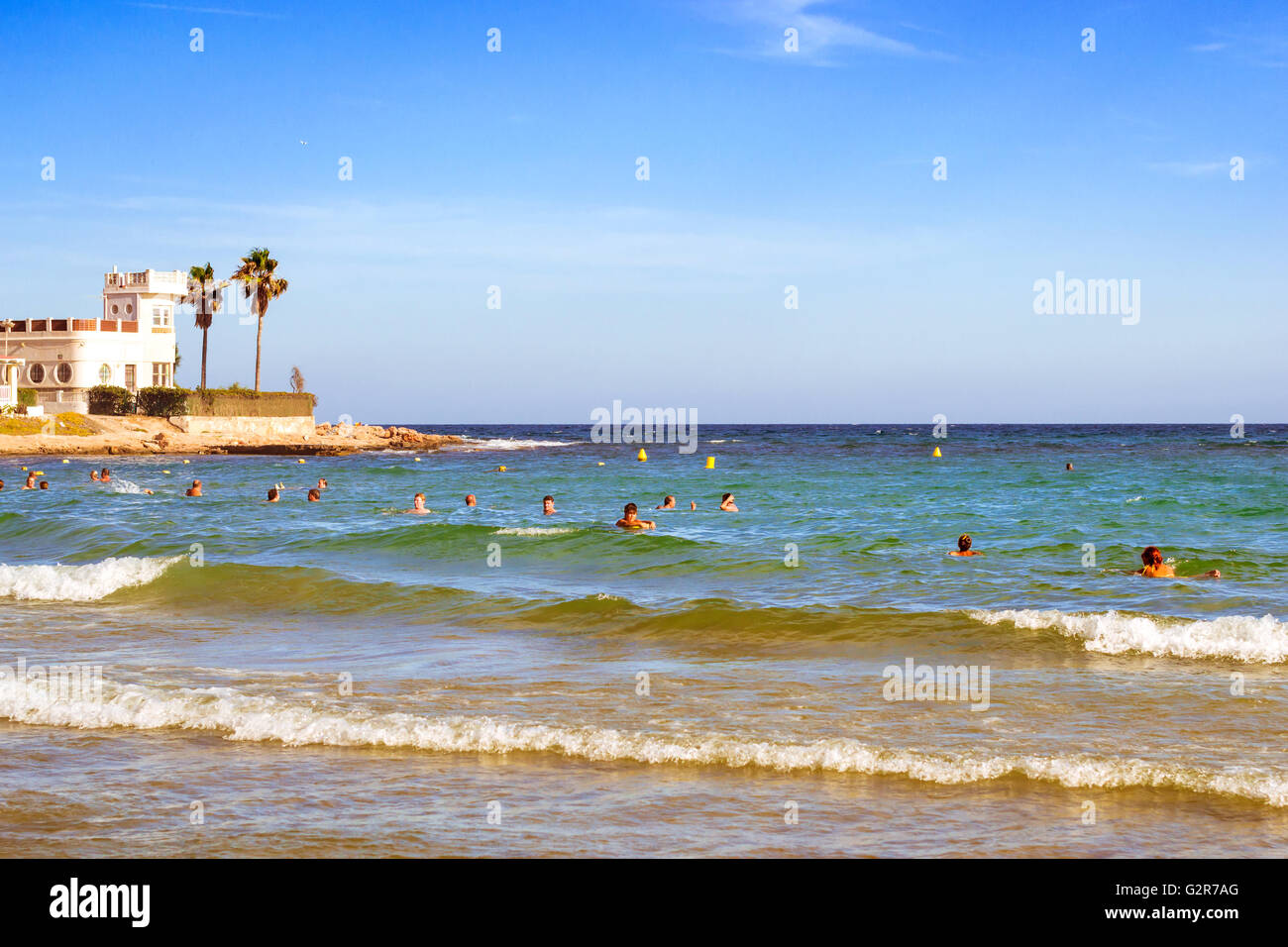 TORREVIEJA, Spanien - 13. September 2014: Sonnige Mittelmeer Strand entspannen Sie Touristen auf Welle. Menschen Baden in kristallklarem Wasser Stockfoto