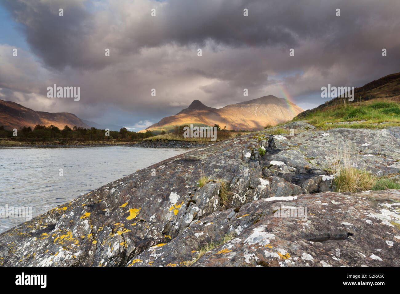 Regenbogen über Pap von Glencoe oder Sgorr Na wölbte Ciche bei unruhigen Wetter mit Granitfelsen und Loch Leven vorne Stockfoto