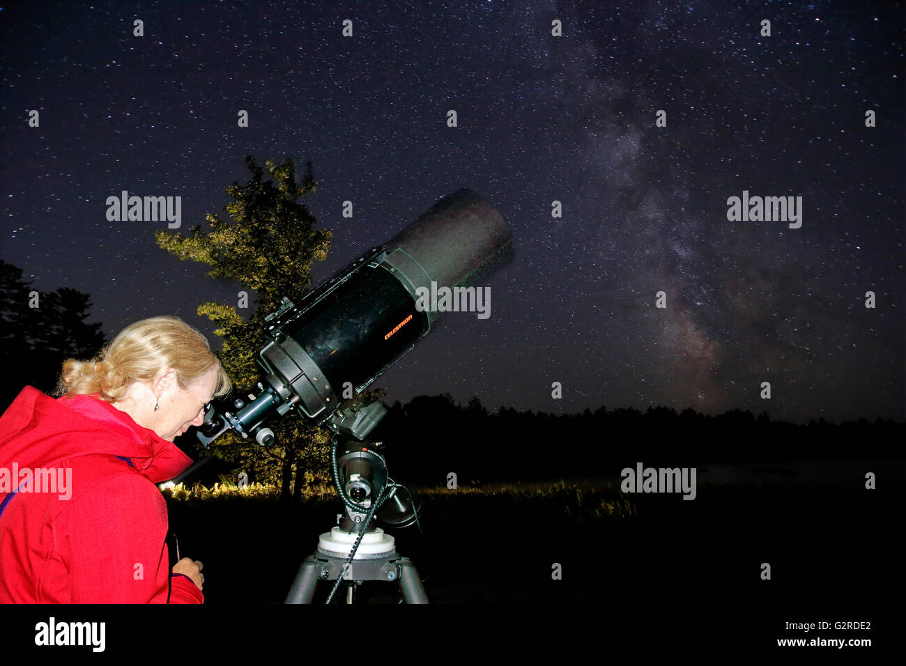 Eine Frau, Blick auf die Sterne und Planeten durch ein Teleskop Stockfoto