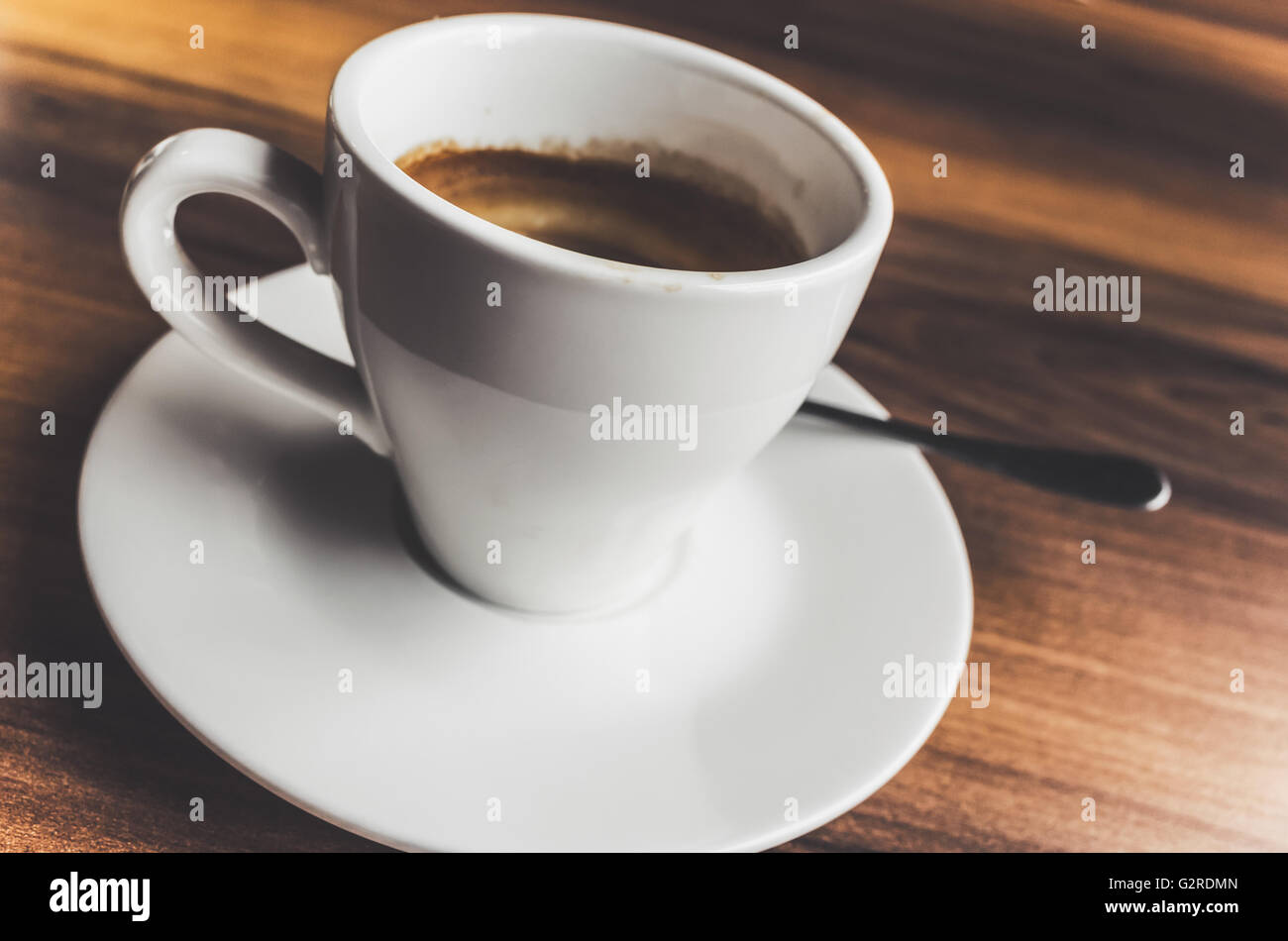 Frisch gebrühter Espressokaffee in weißen Tasse auf Untertasse mit Löffel. Nahaufnahme Foto mit Tiefenschärfe und Vintage tonale correctio Stockfoto