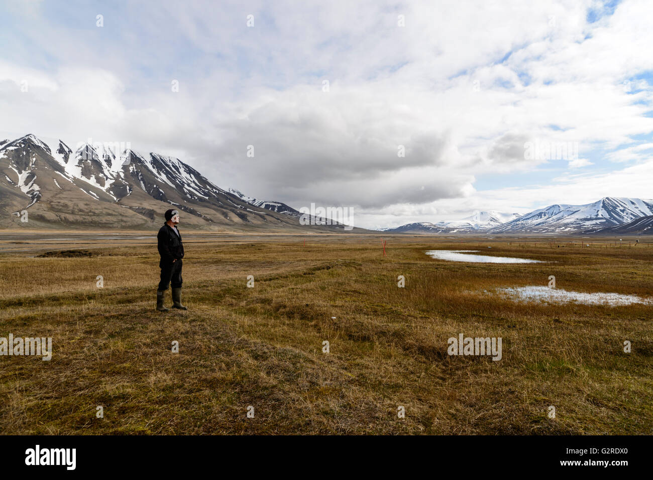Ein Mann steht auf der arktischen Tundra von Adventdalen, Longyearbyen, Spitzbergen, Svalbard, Norwegen Stockfoto