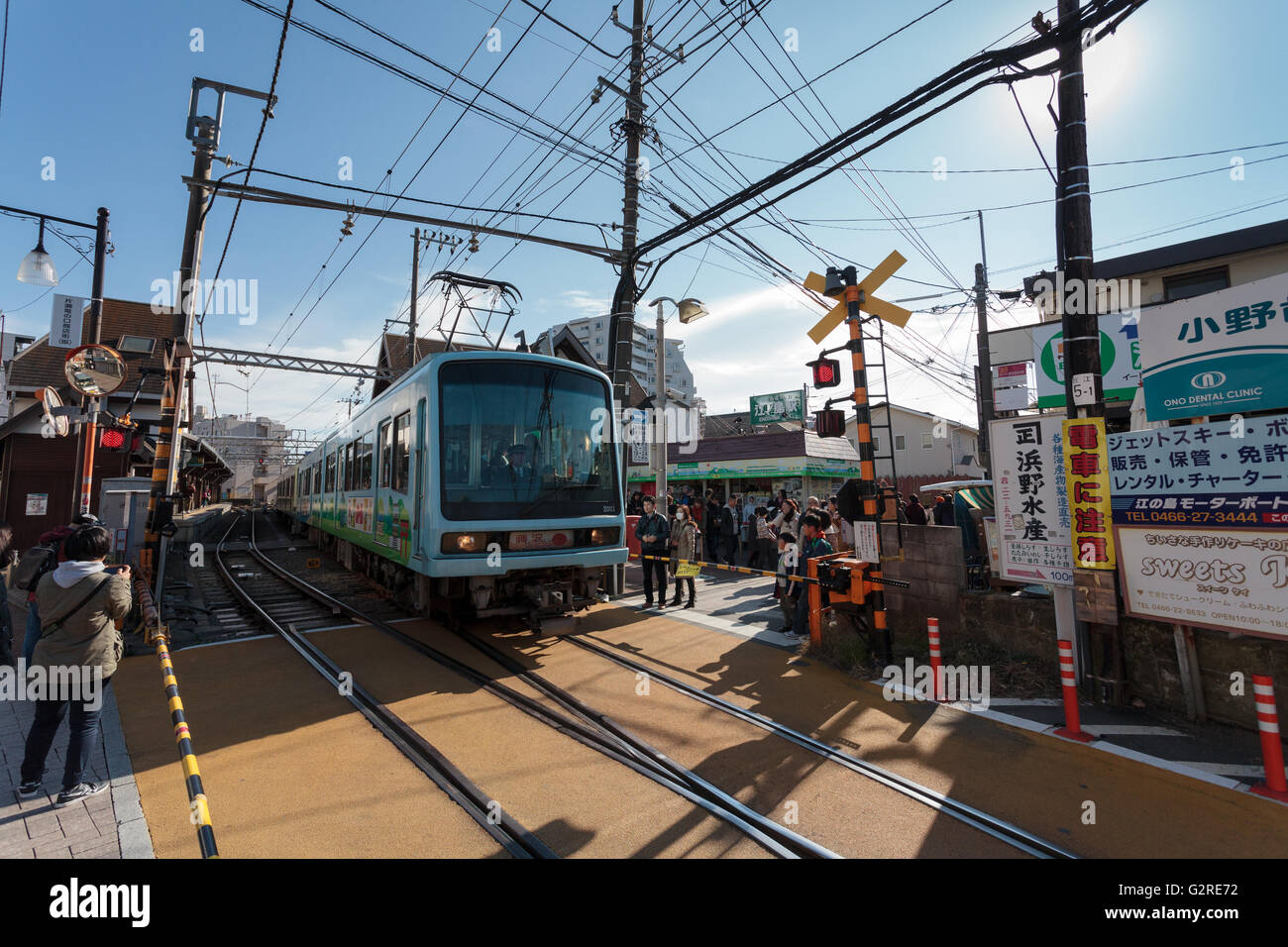Ein Zug auf der Enoden-Bahnlinie an einer Kreuzung in der Nähe der Enoshima-Station, Kanagawa, Japan. Stockfoto