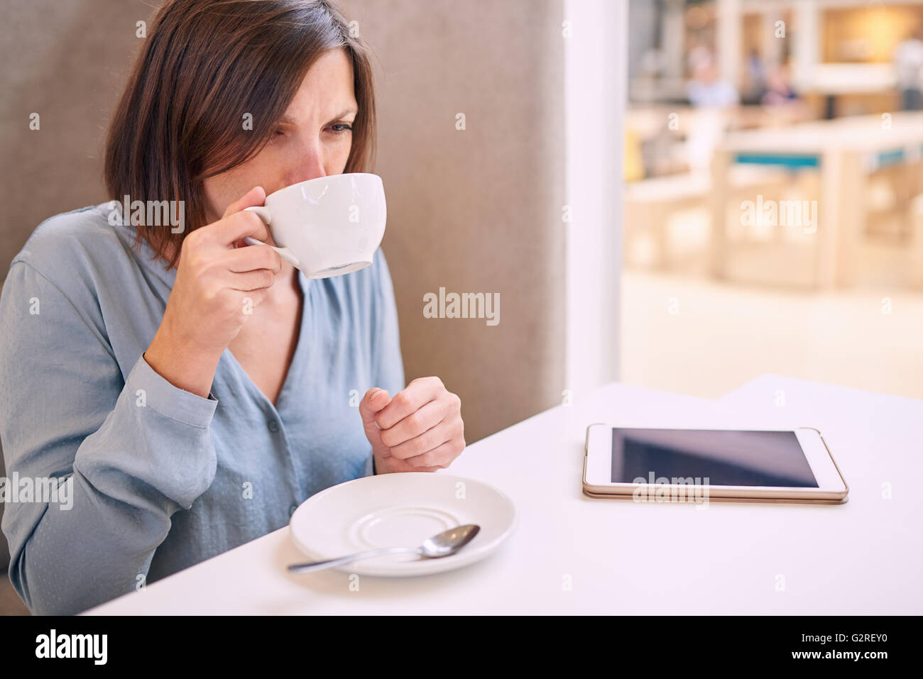 Frau Cappaccino in einem hellen Café mit Tablet schlürfen Stockfoto