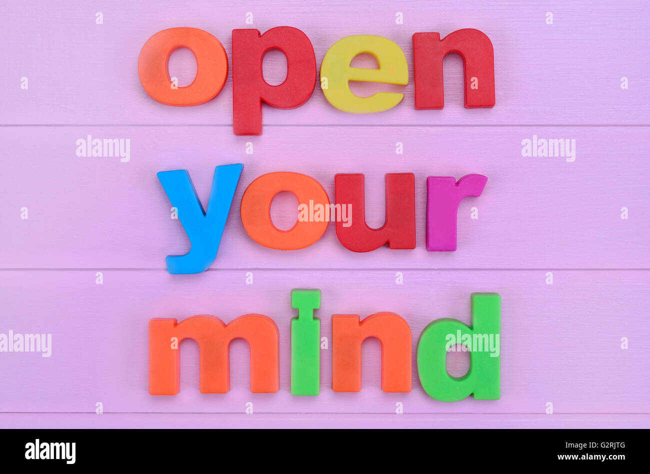 Die Worte öffnen Sie Ihren Geist auf rosa Holztisch Stockfoto