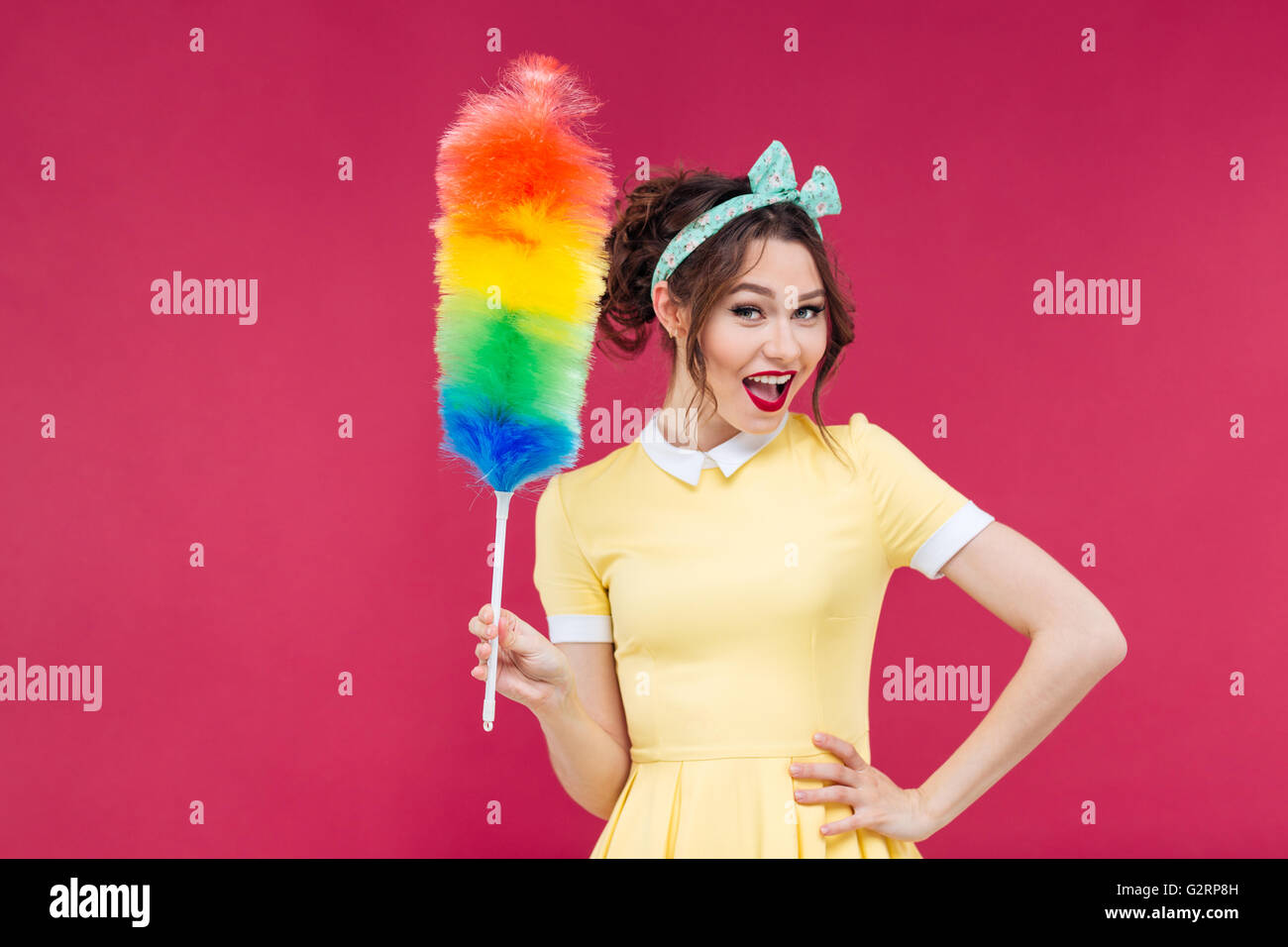 Lächelnd attraktive Pinup-Girl mit bunten Duster Pinsel über rosa Hintergrund Stockfoto