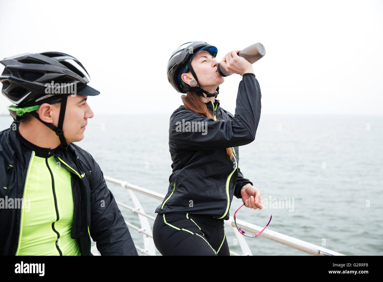 Zwei Radfahrer ruht in der Nähe von Meer. Trinkwasser für Frau und Mann sah auf dem Meer Stockfoto