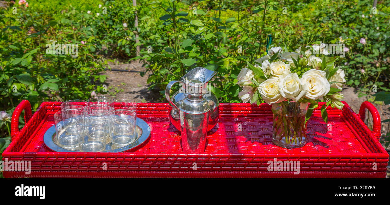 Top Tischdekoration bestehend aus einem silbernen Tablett mit Gläsern, silbernen Krug, Silber cocktail-Shaker und Vase mit frisch geschnittenen Rosen Stockfoto