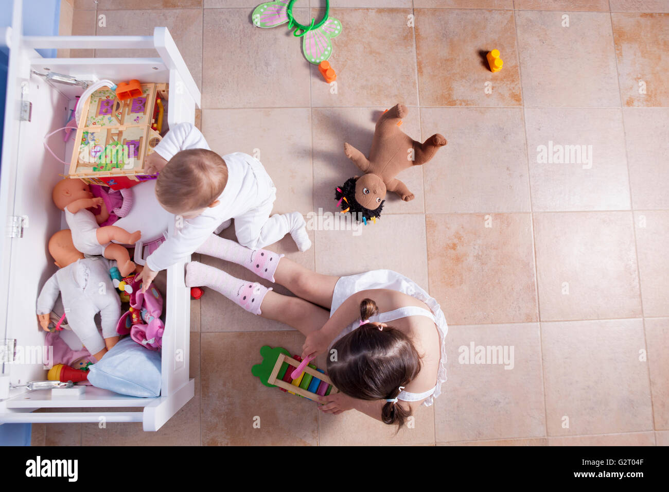 Jungen spielen mit seiner Schwester im Zimmer Spielzeug. Sie nehmen Spielsachen aus ihrem Stamm. Erhöhte Ansicht Stockfoto