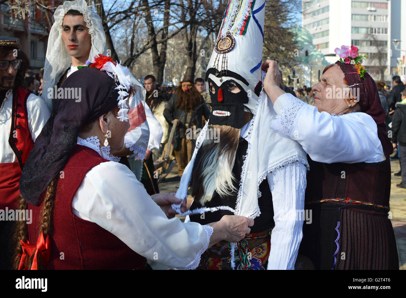 Einheimische Frauen mit traditionellen Trachten und Masken der Kukeri am Surva Festival in Pernik, Bulgarien Stockfoto