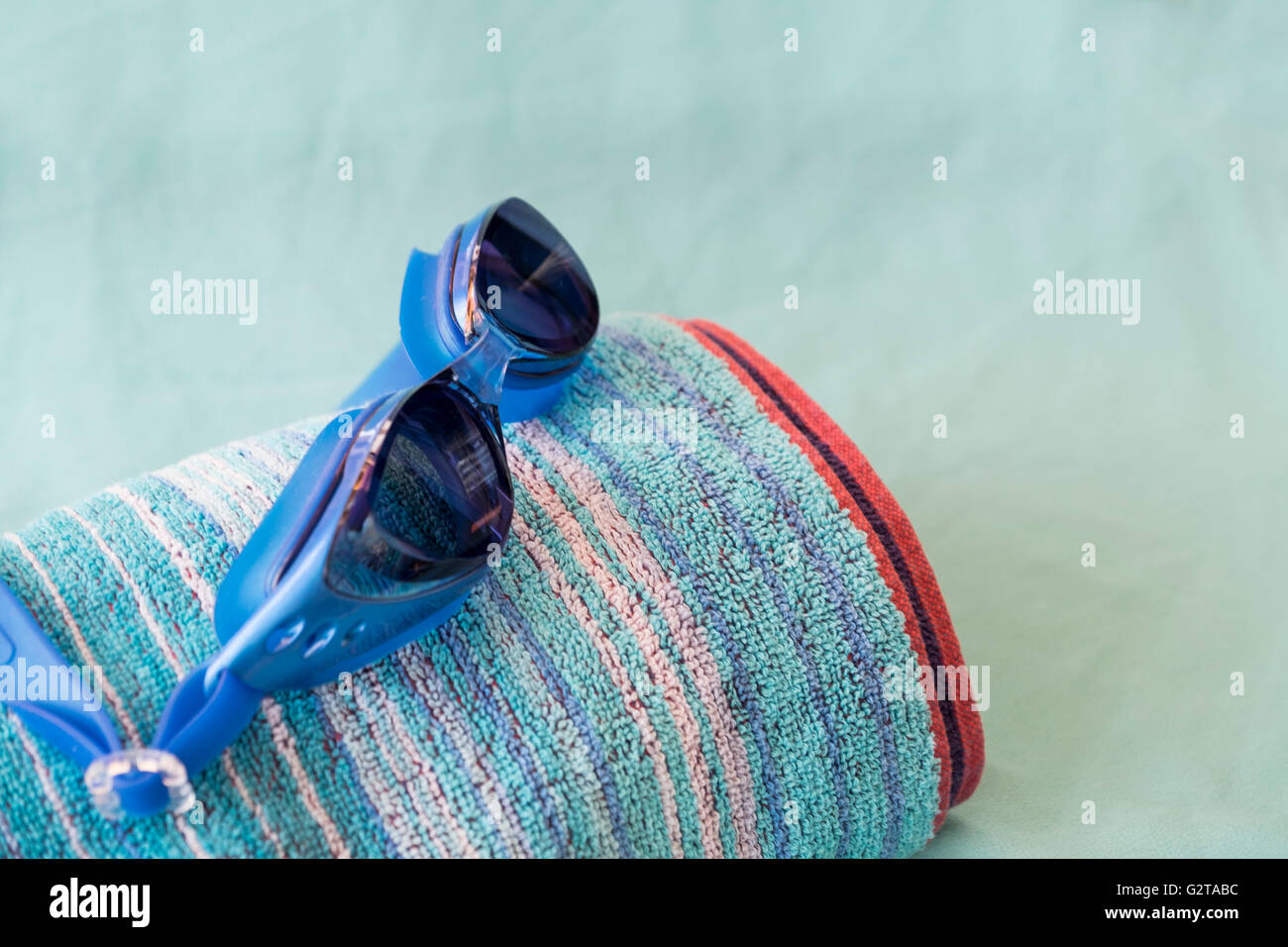 Schwimmbrillen und Strandtuch auf türkis blauem Hintergrund Stockfoto