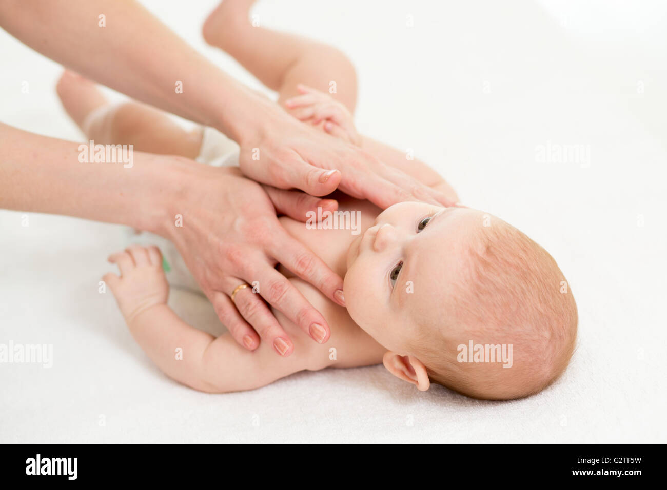 Baby-Massage. Mutter oder Masseur massiert Kind. Stockfoto