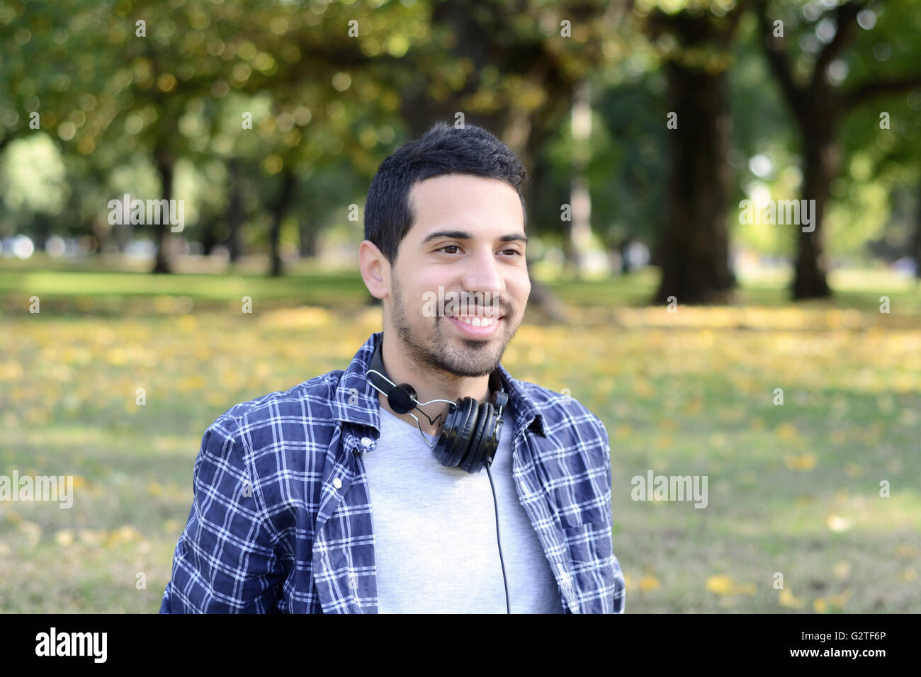 Nahaufnahme eines schönen jungen Mann mit Kopfhörern in einem Park. Im Freien. Stockfoto