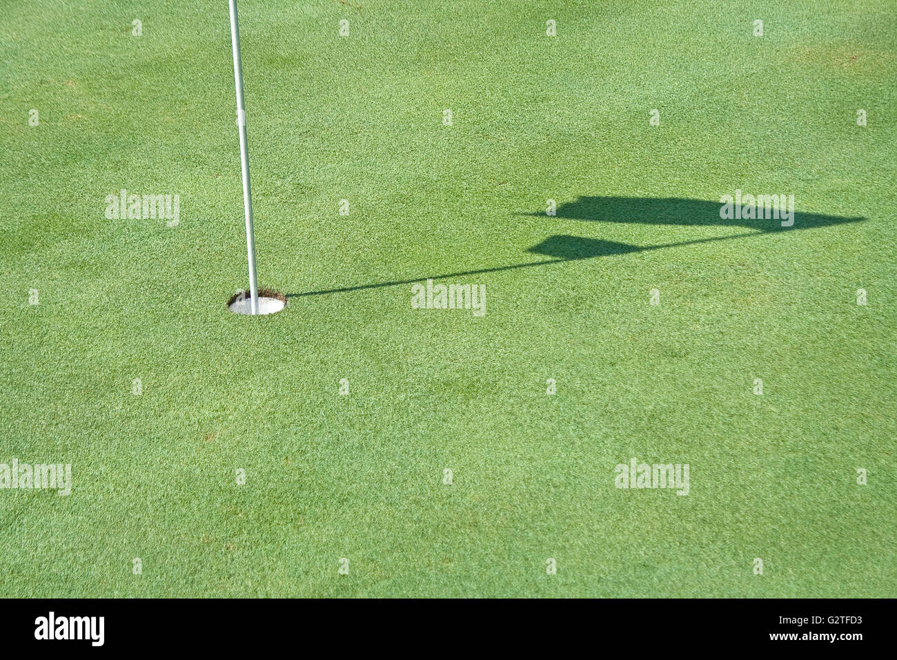 Loch und Schatten des Golf Flagge winken Stockfoto