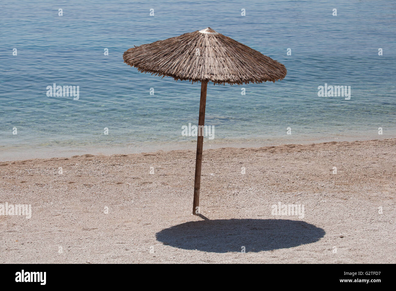 Einsam aus Holz Sonnenschirm an einem sonnigen Strand nahe am Meerwasser setzen. Stockfoto