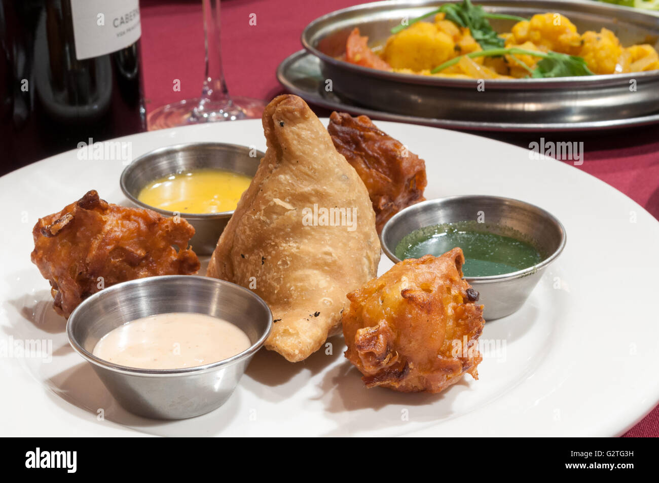 Authentische handgefertigten indischen Samosas, mit 3 Saucen mit Wein und Gemüse serviert. Stockfoto