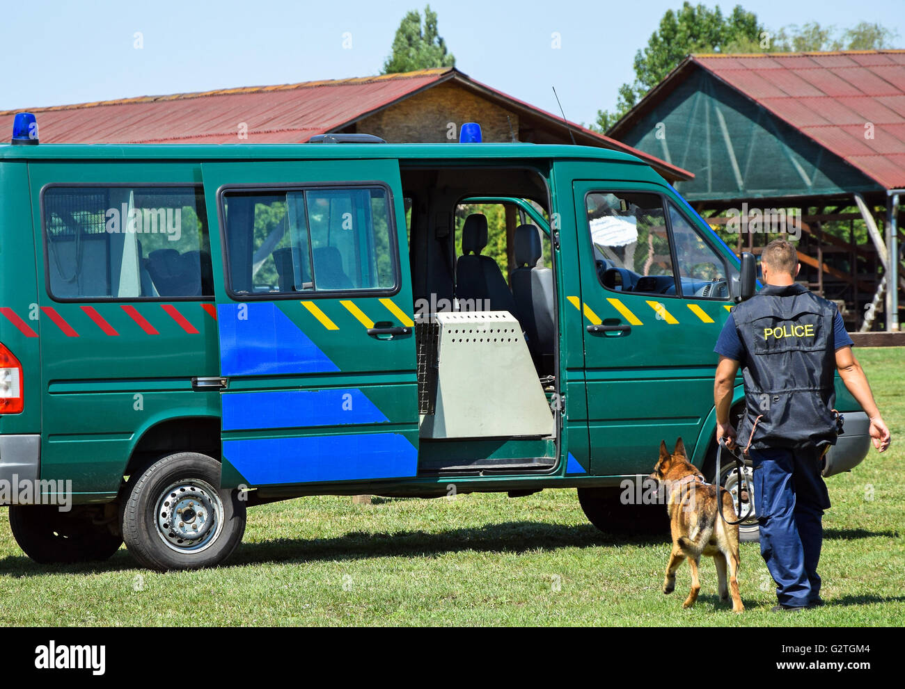 Polizist mit seinem Hund neben den Streifenwagen Stockfoto
