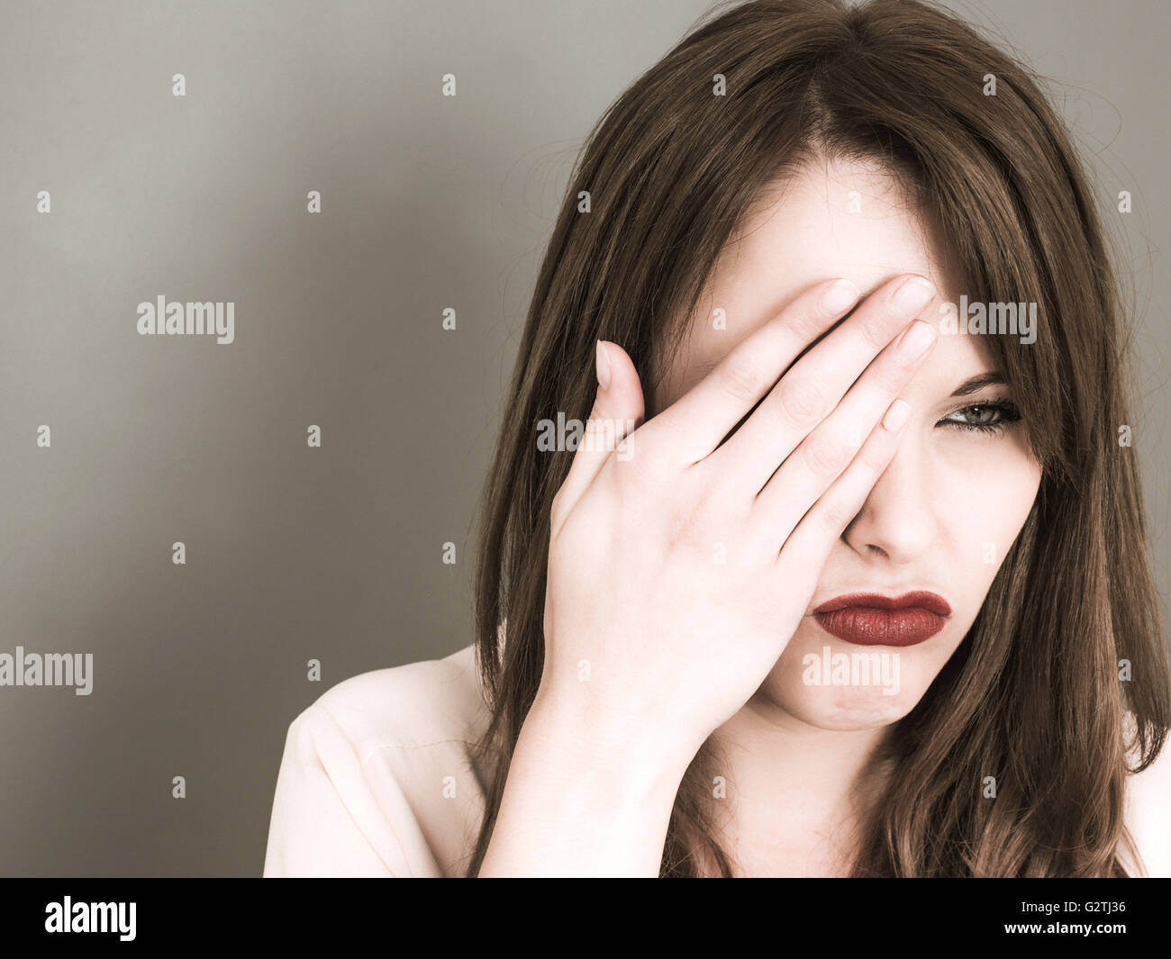 Creative Portrait einer jungen kaukasischen Frau, die ihr rechtes Auge mit ihrer Hand sieht miserabel und besorgt Stockfoto