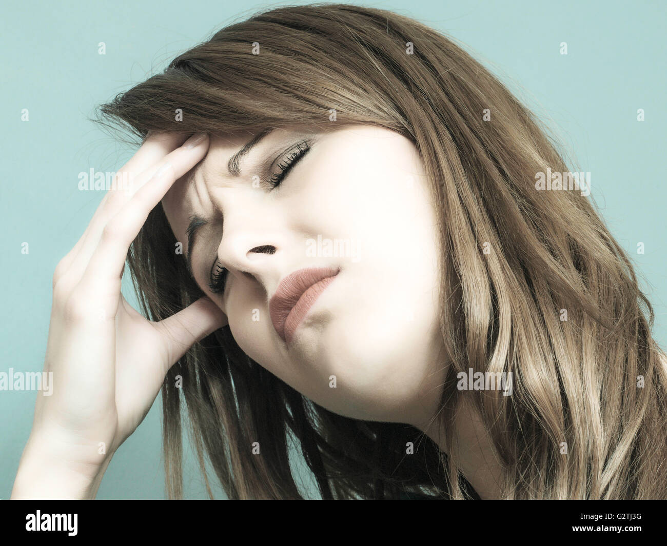 Kreative Toned Porträt eine attraktive junge Caucasian Frau auf der Suche gestresst und erschöpft oder unwohl Stirnrunzeln Stockfoto