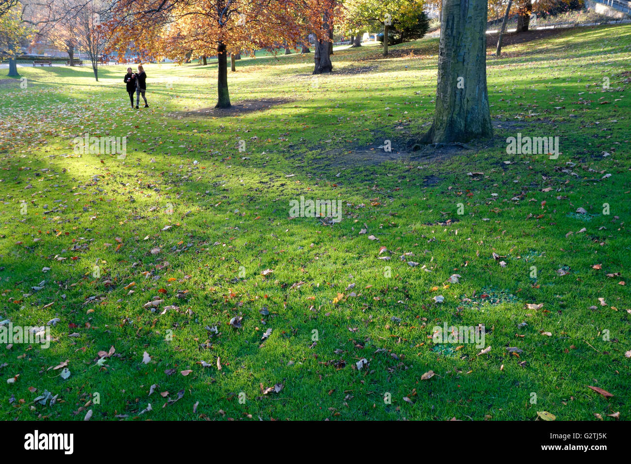 Junge Frauen gehen durch eine herbstliche Princes Street Gardens, Edinburgh Stockfoto