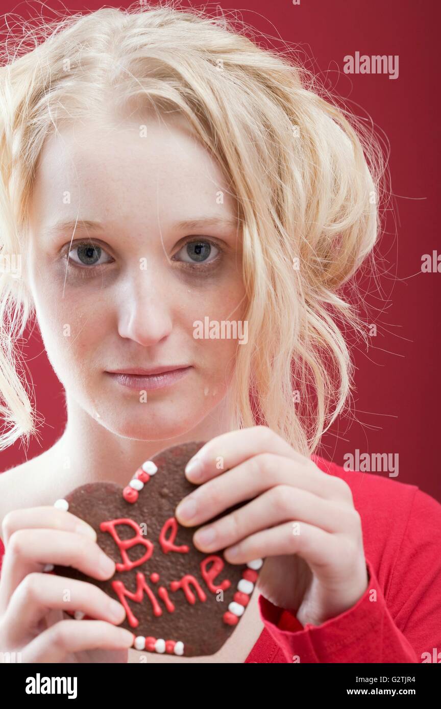 Traurige junge Frau mit Schokolade zum Valentinstag Herz Stockfoto