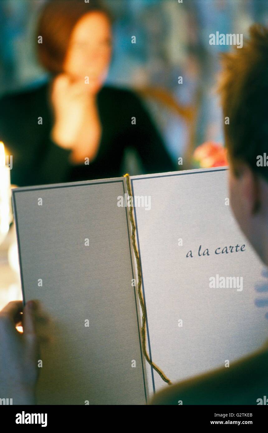 Mann liest Menü im Restaurant mit Frau im Hintergrund Stockfoto
