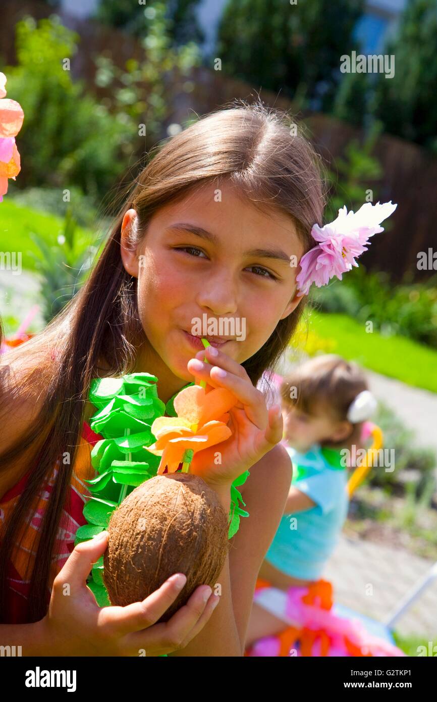 Mädchen trinken Kokosmilch aus Kokosnuss am Kinderfest Stockfoto