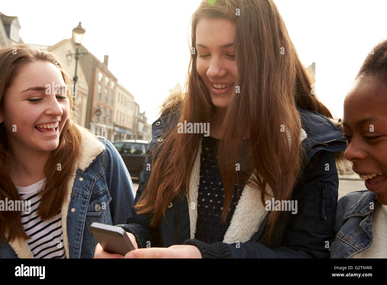 Mädchen im Teenageralter zu Fuß entlang der Straße mit Blick auf Social Media Stockfoto