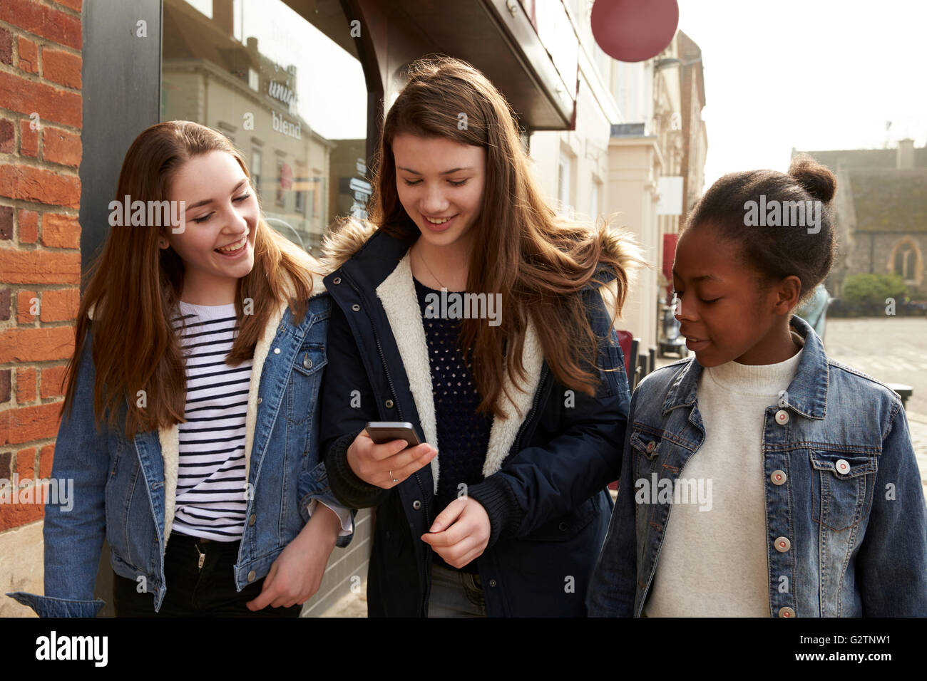 Mädchen im Teenageralter zu Fuß entlang der Straße mit Blick auf Social Media Stockfoto